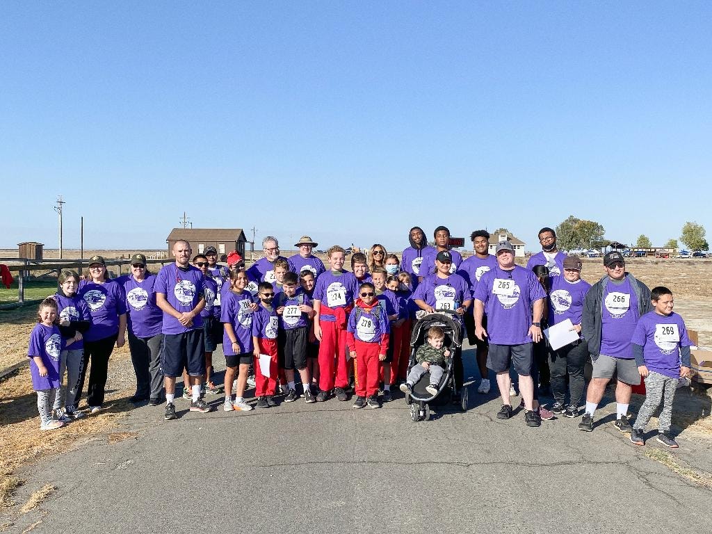 Group photo of participants in purple Colonel Allensworth 5K shirts at the park